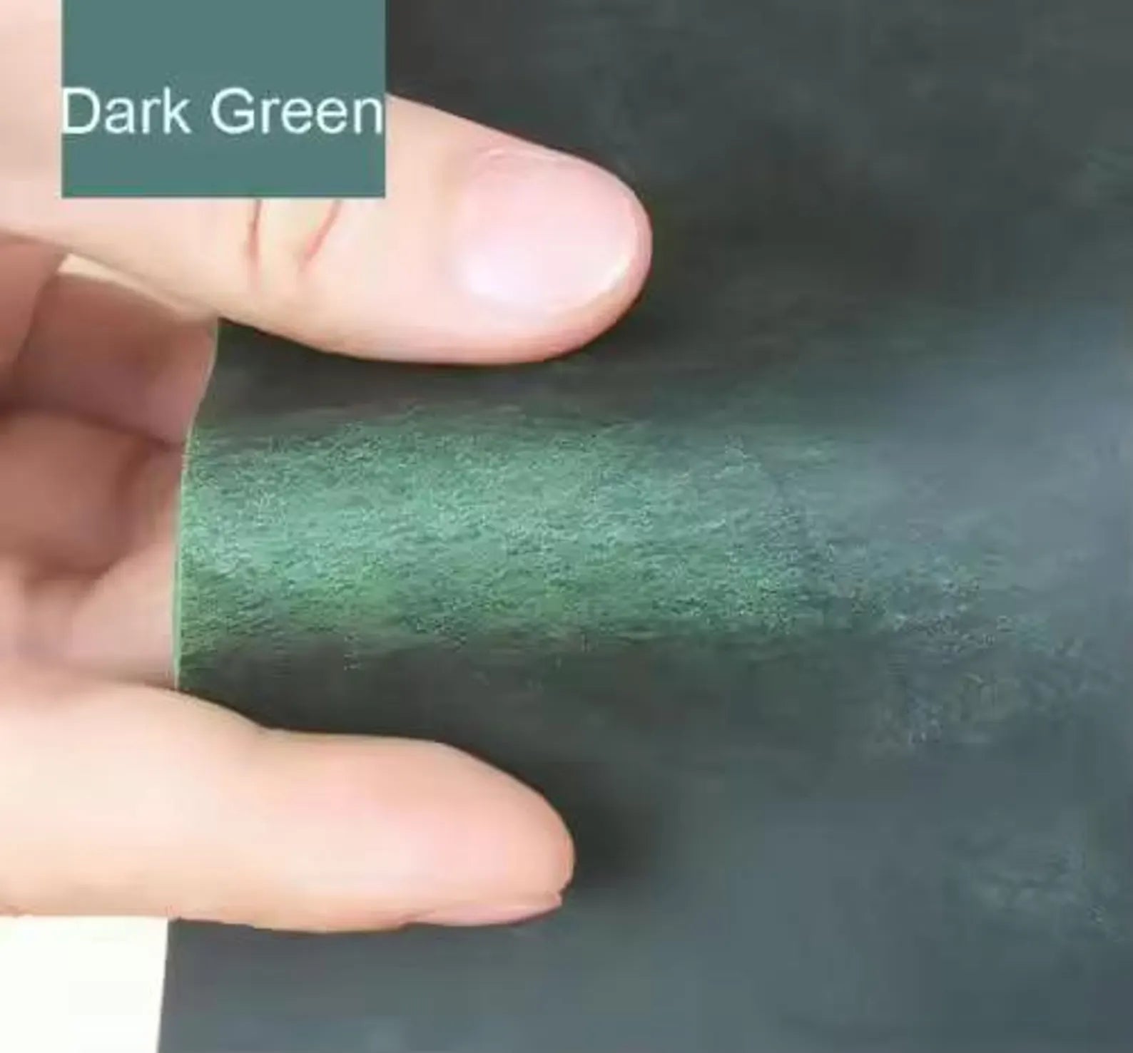 Dark green leather swatch with a hand for scale