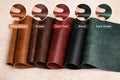 Five rolls of leather in different colors with color swatches above them on a beige background.