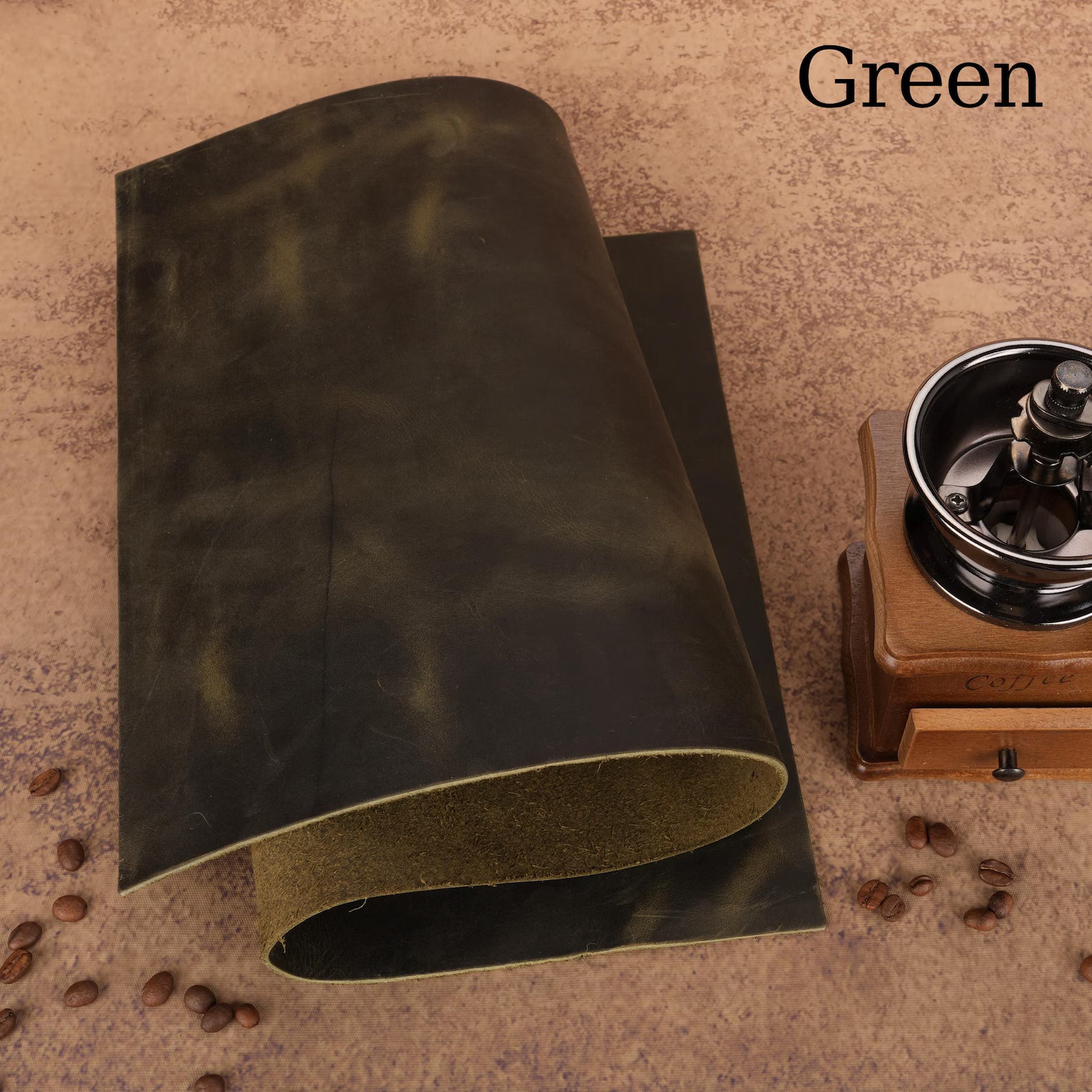 Green leather sample with a coffee grinder and beans on a textured surface